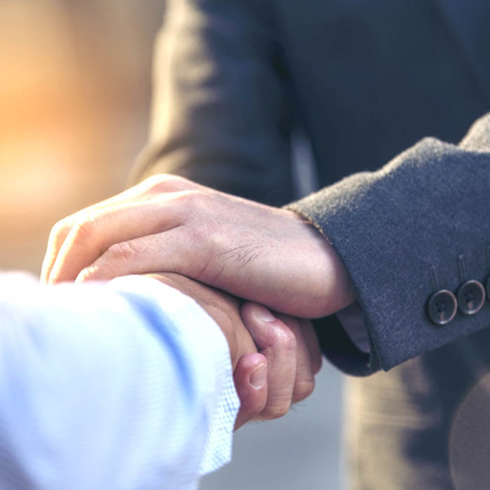 Two men in suits shaking hands, focus on just hands